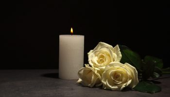 Photo-pour-Belles-roses-blanches-et-bougie-sur-table-sur-fond-noir.-Symbole-funéraire---image-libre-de-droit